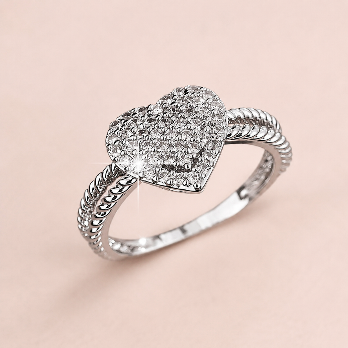 Anillo de corazón con cristales sobre fondo rosa nude, blanco y beige