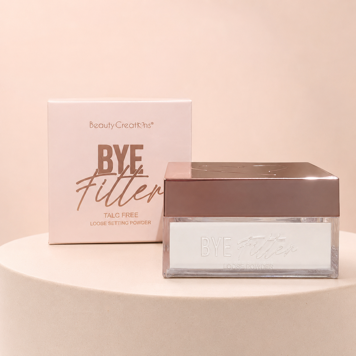 Polvo traslúcido BYE Filter de Beauty Creations sobre fondo rosa nude, blanco y beige