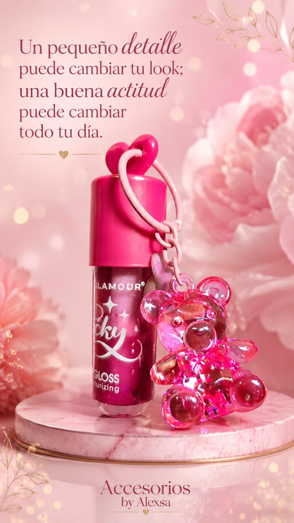 Brillo labial rosa de Accesorios by Alexsa con llavero de osito translúcido sobre base de mármol y fondo floral.