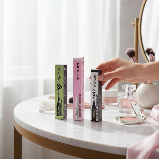 Accesorios by Alexsa Moira liquid eyeliner pens in green, pink, and black boxes on a marble vanity table
