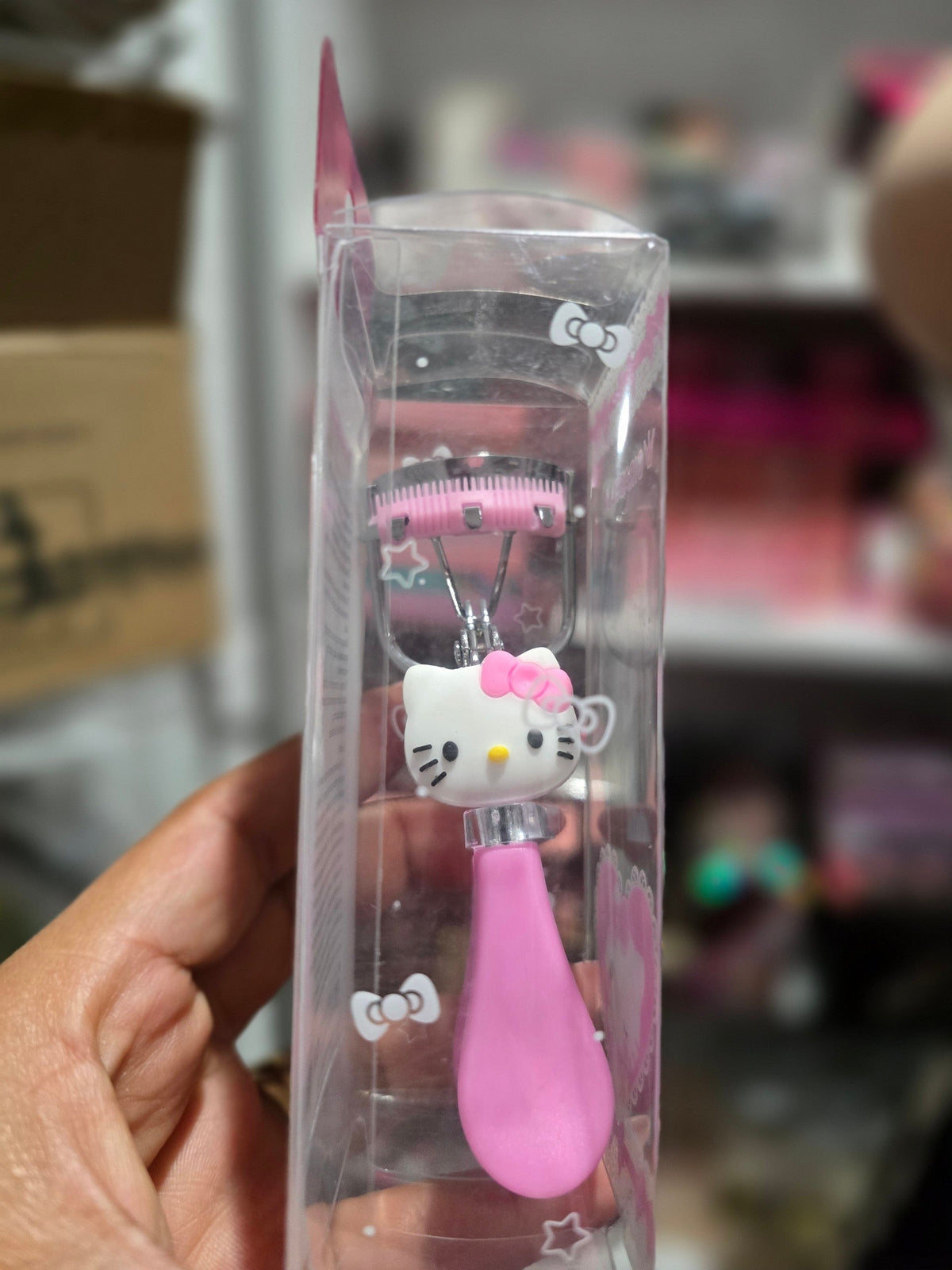 Accesorios by Alexsa eyelash curler with a pink handle and Hello Kitty character design in clear retail packaging.