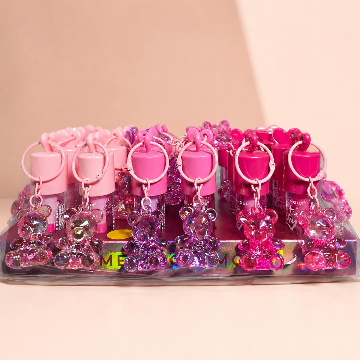 Set de brillos labiales Accesorios by Alexsa con llaveros de ositos en tonos rosa y fucsia sobre base exhibidora