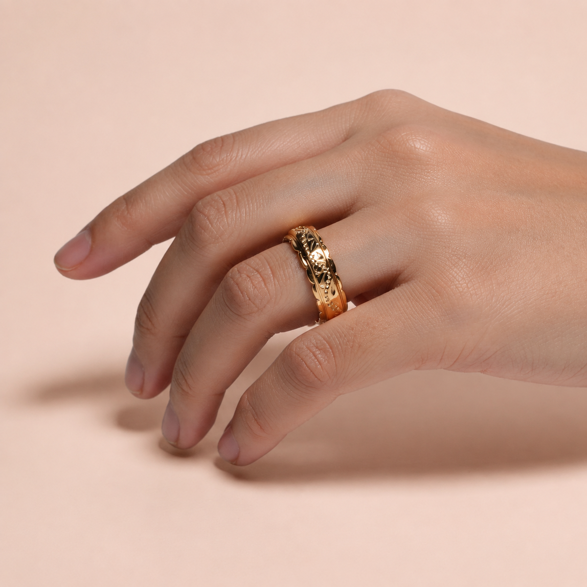 Anillo de argolla grabada sobre fondo rosa nude, blanco y beige