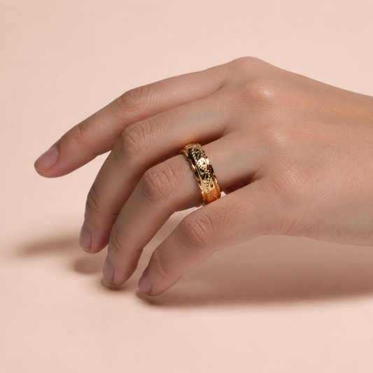 Anillo de argolla grabada sobre fondo rosa nude, blanco y beige