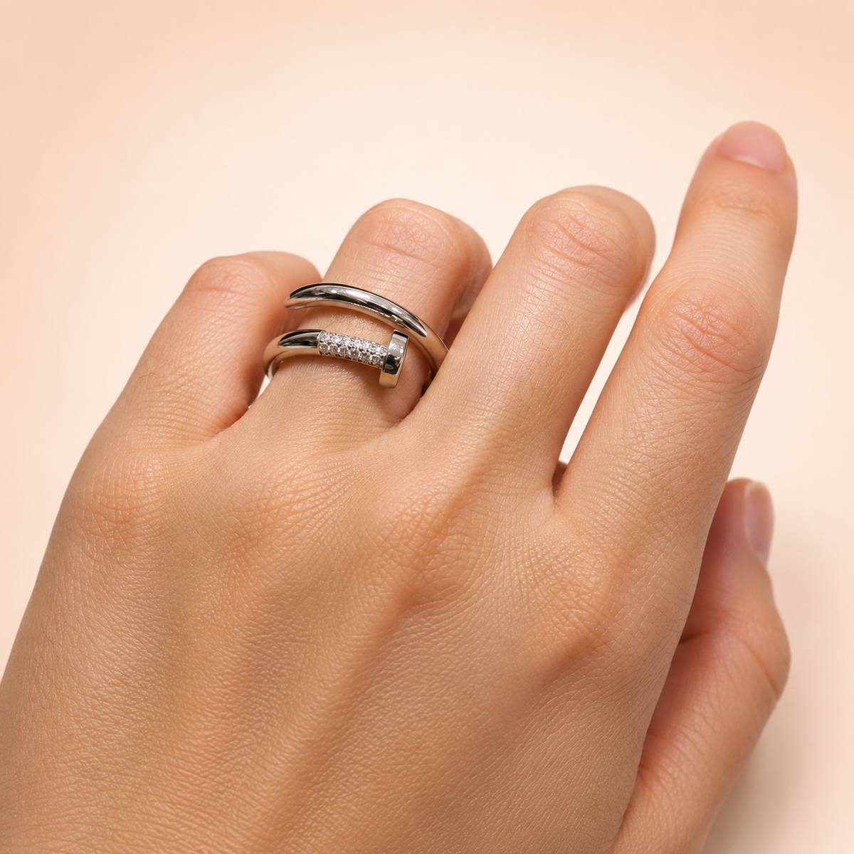Anillo Forma de Clavo de Plata 925 sobre fondo rosa nude, blanco y beige