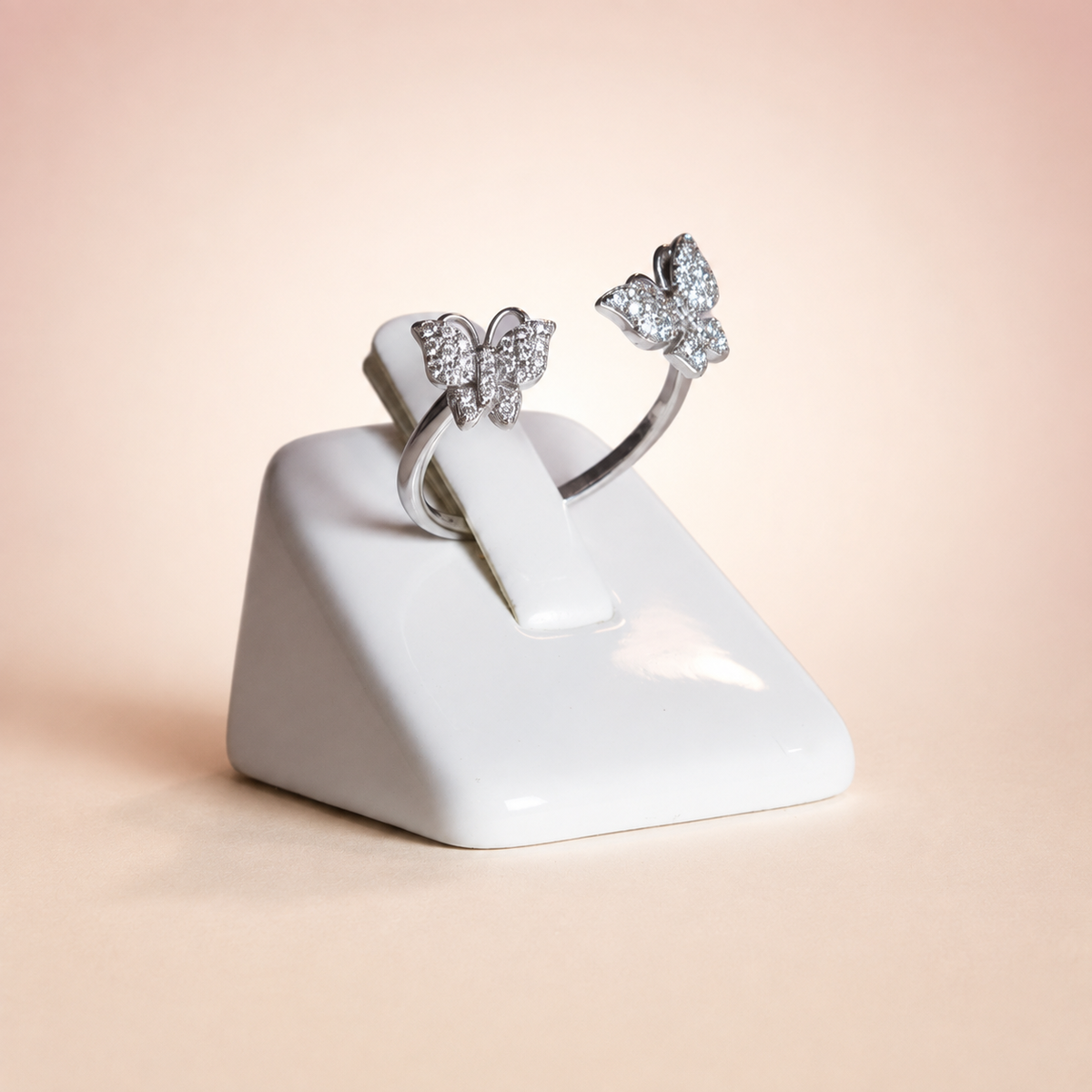 Anillo Forma Mariposa Plata 925 sobre fondo rosa nude, blanco y beige