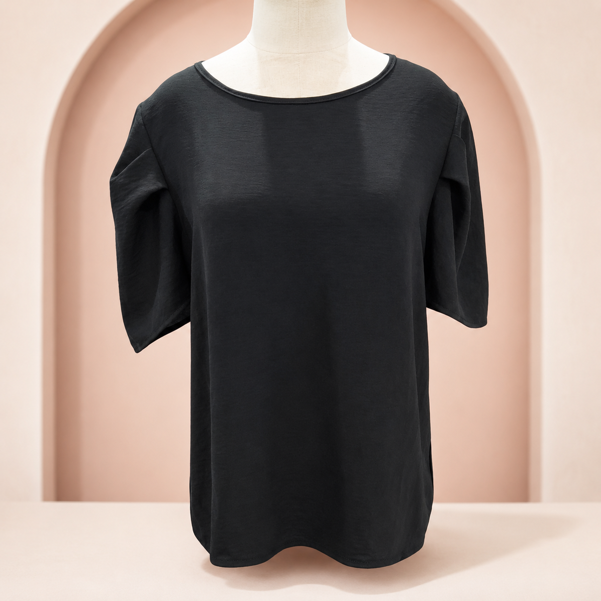 Blusa de vestir negra con botón atrás en fondo rosa nude, blanco y beige