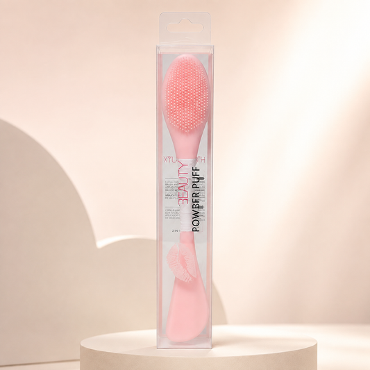Espátula y cepillo limpiador HUDA rosa claro en empaque sobre fondo rosa nude, blanco y beige