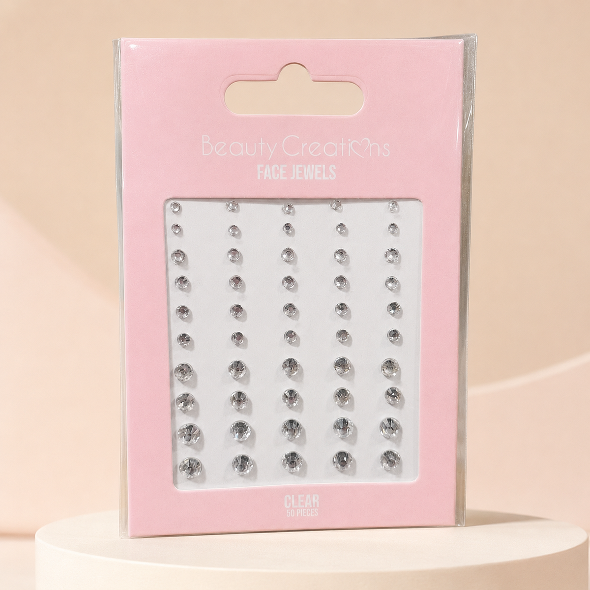 Face Jewels Clear de Beauty Creations sobre fondo rosa nude, blanco y beige