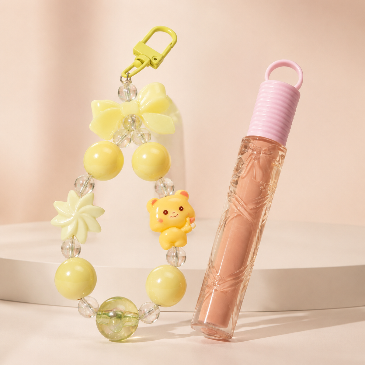 Llavero de cuentas amarillo nude con gloss sobre fondo rosa nude, blanco y beige