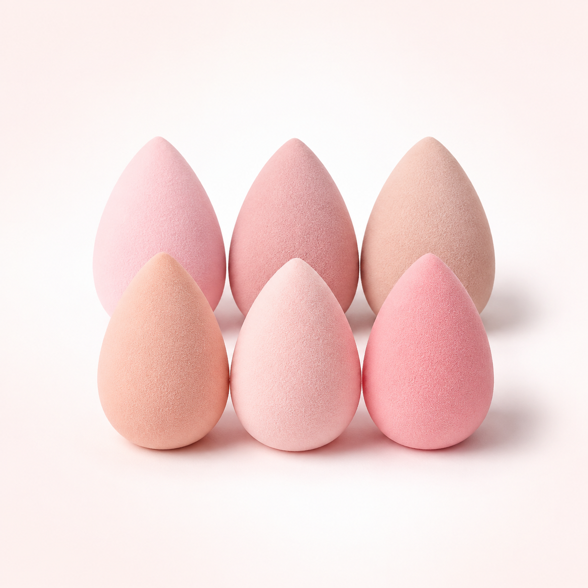 Set de esponjas difuminadoras en tonos rosa y nude sobre fondo blanco cálido